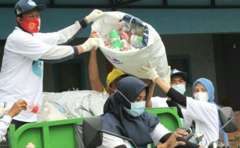 Ning Nurul membantu menaikkan sampah plastik dalam memeriahkan HPSN yang digelar DLH Gresik dan Asbag di Desa Ngargosari, Kecamatan Kebomas pada Sabtu, 20 Februari 2021 ( foto : chusnul cahyadi/1minute.id)