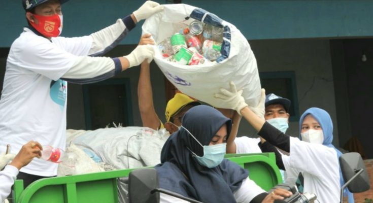 Ning Nurul membantu menaikkan sampah plastik dalam memeriahkan HPSN yang digelar DLH Gresik dan Asbag di Desa Ngargosari, Kecamatan Kebomas pada Sabtu, 20 Februari 2021 ( foto : chusnul cahyadi/1minute.id)