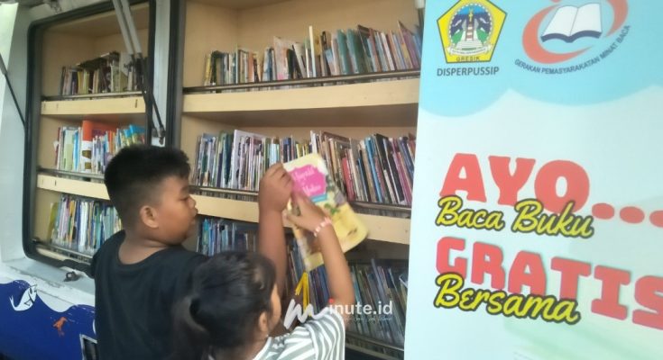 Dua anak sedang memilih buku bacaan di mobil perpustakaan milik Dinas Perpustakaan dan Kearsipan Gresik di arena car free day Jalan Jaksa Agung Suprapto, Gresik (Foto : Chusnul Cahyadi/1minute.id)